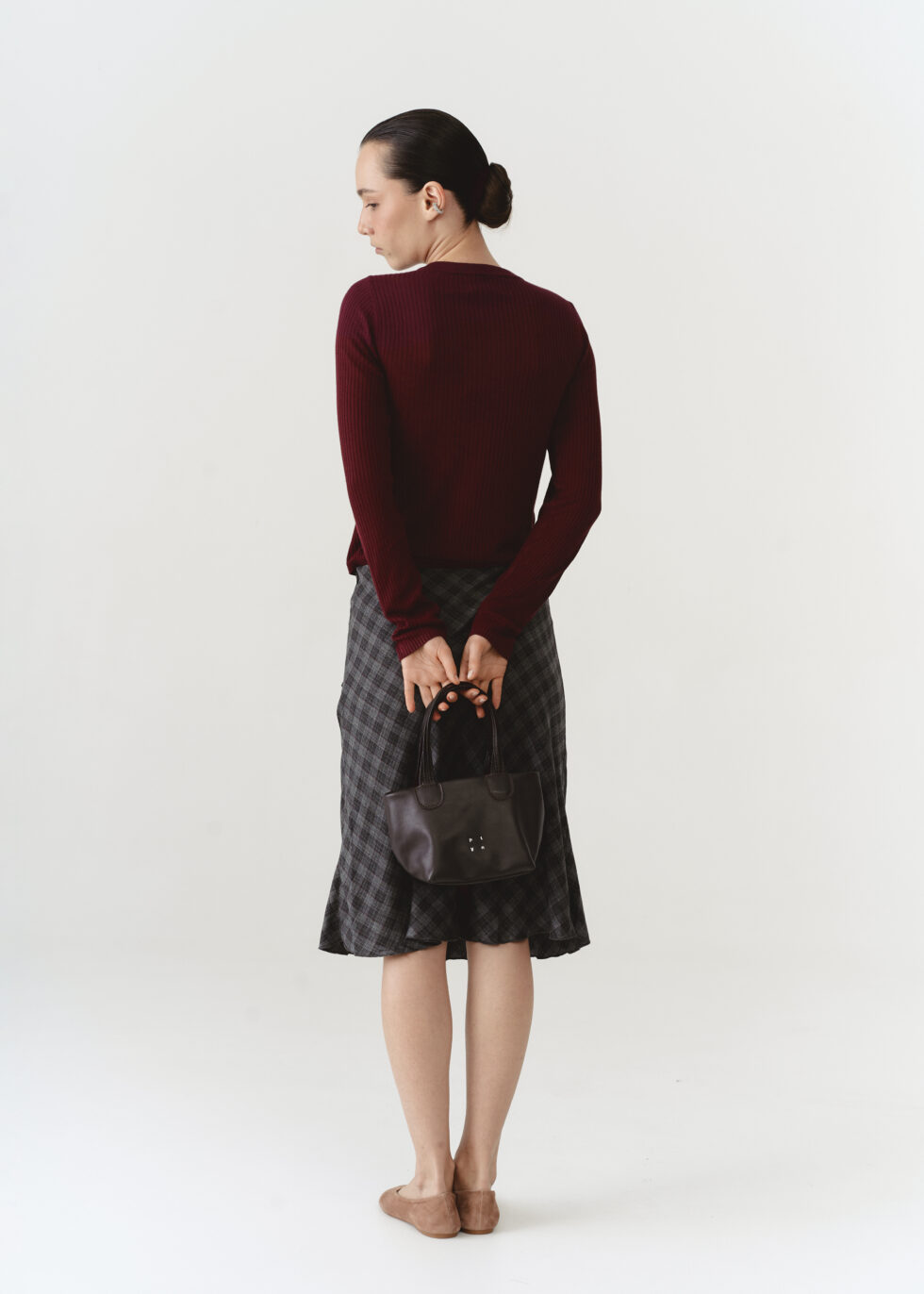 Коричнева шкіряна міні-тоут з плетеними ручками в руках моделі