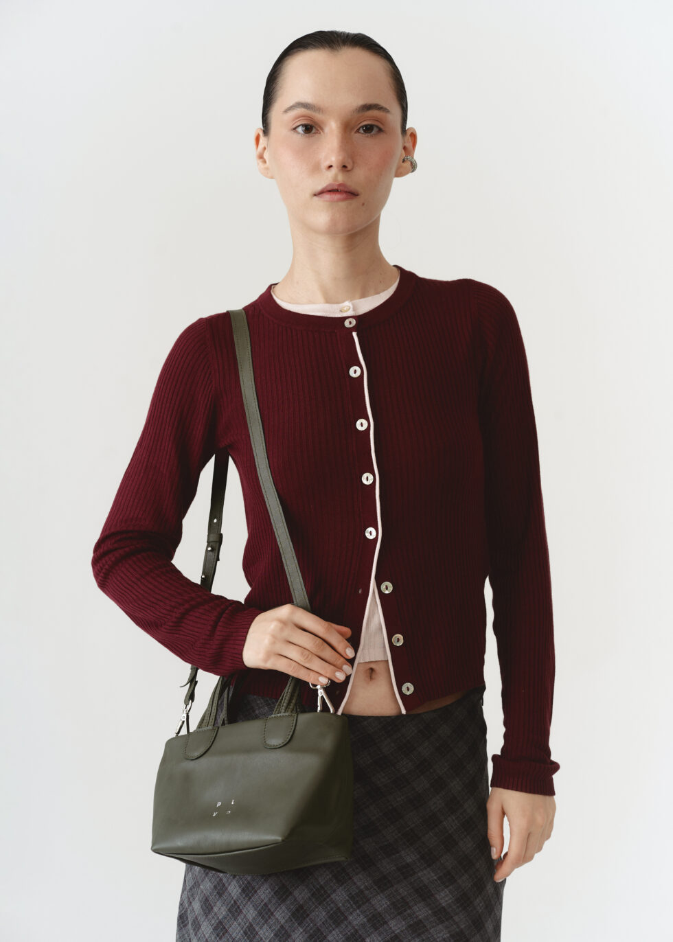 Шкіряна кросбоді хакі з плетеними ручками на плечі моделі